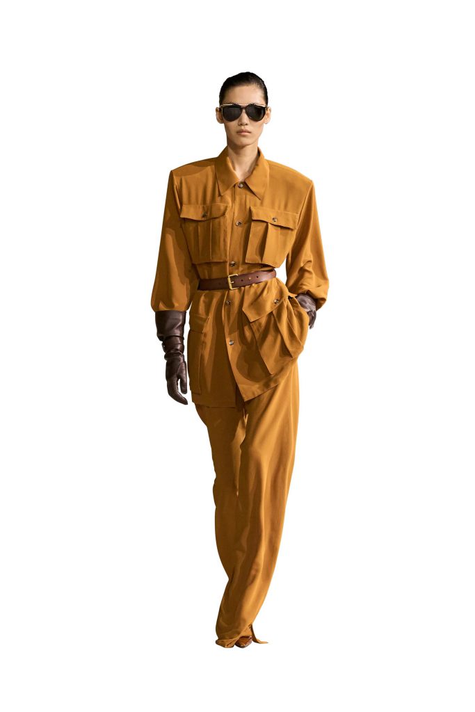Người mẫu mặc bộ trang phục màu nâu vàng với kính râm và găng tay da