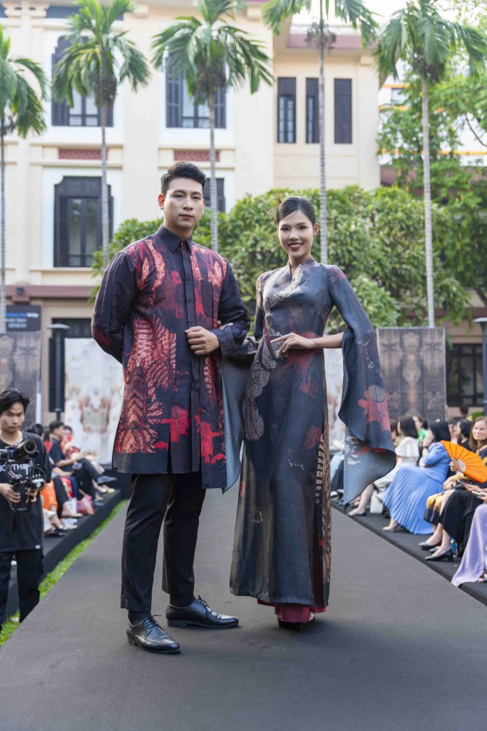 Người mẫu nam và nữ trình diễn trang phục lụa truyền thống trên sàn catwalk ngoài trời