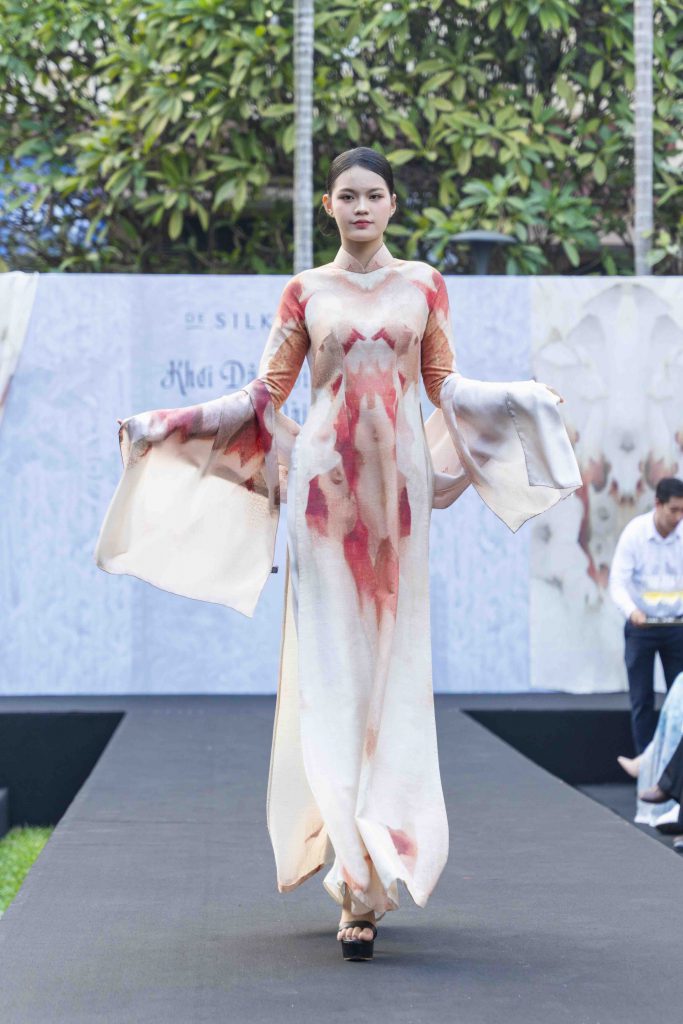 Người mẫu trình diễn áo dài lụa họa tiết hoa lá trên sàn catwalk