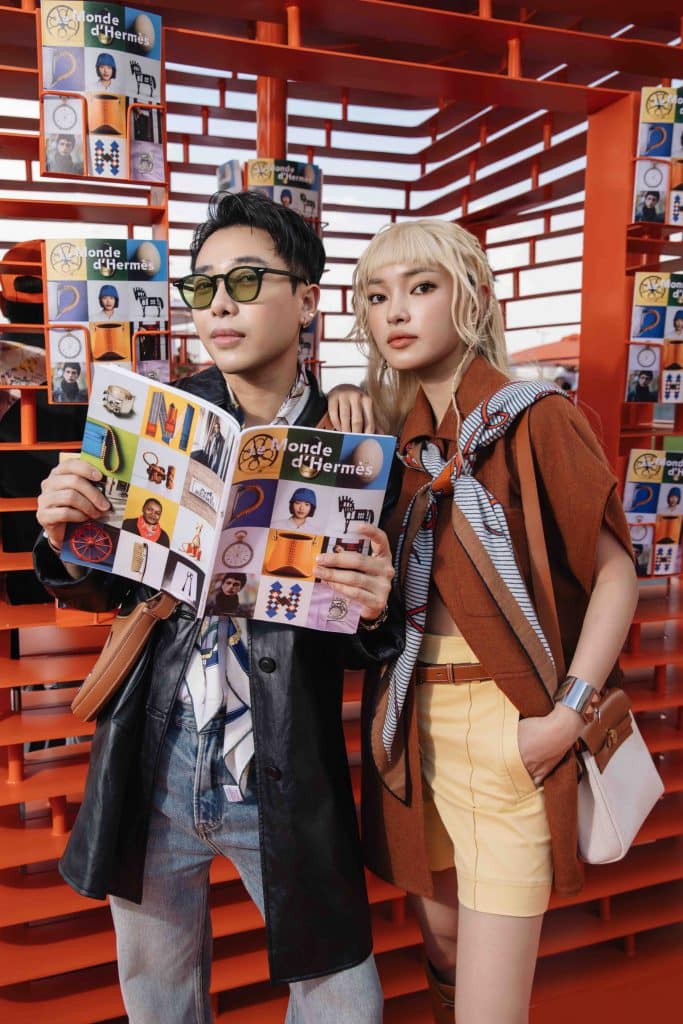 Nam nữ trẻ trung cầm tạp chí tại quầy Hermès màu cam nổi bật ở Thành phố Hồ Chí Minh
