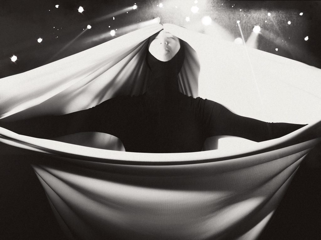 Một người nằm trong lớp vải trắng mềm mại dưới ánh sáng rực rỡ