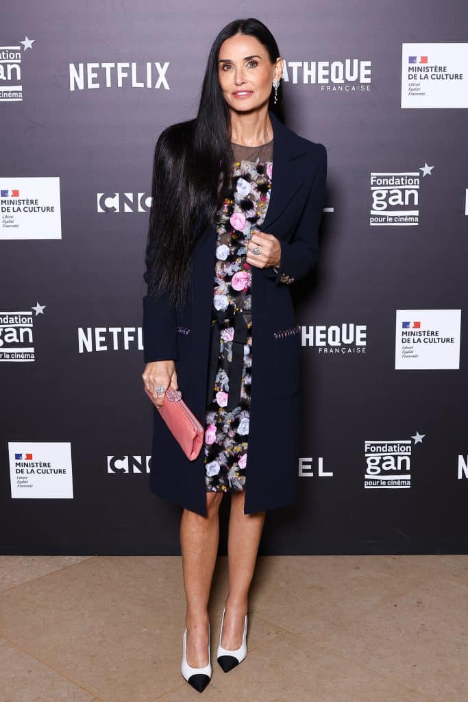 Demi Moore mặc váy hoa và áo khoác đen trên thảm đỏ sự kiện điện ảnh