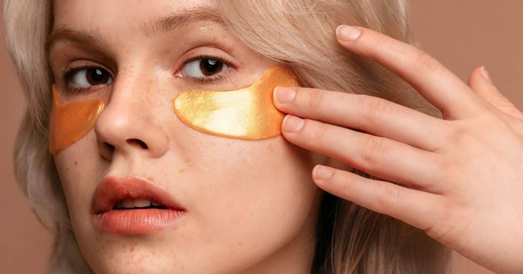 Cô gái trẻ với miếng dán mắt vàng kim và tay che má