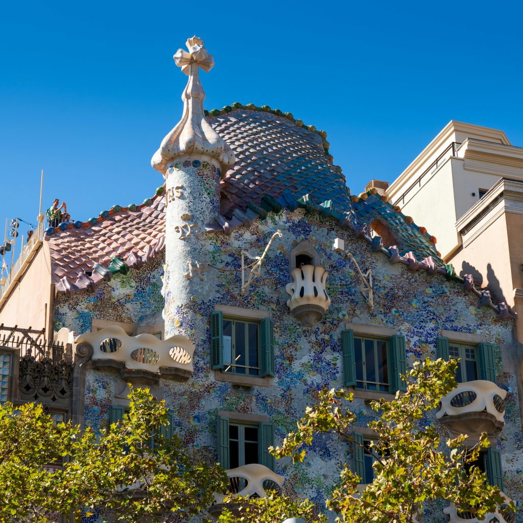 A colorful building facade features ornate tilework and unique architectural details under a bright blue sky