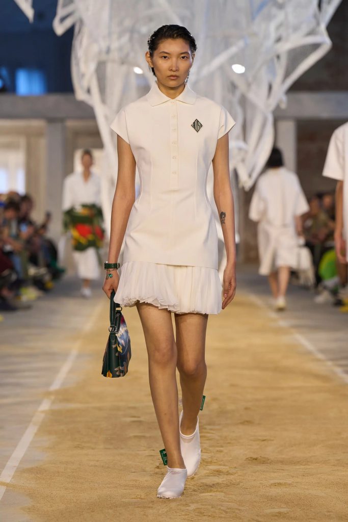 Người mẫu trình diễn váy trắng polo trên sàn diễn thời trang