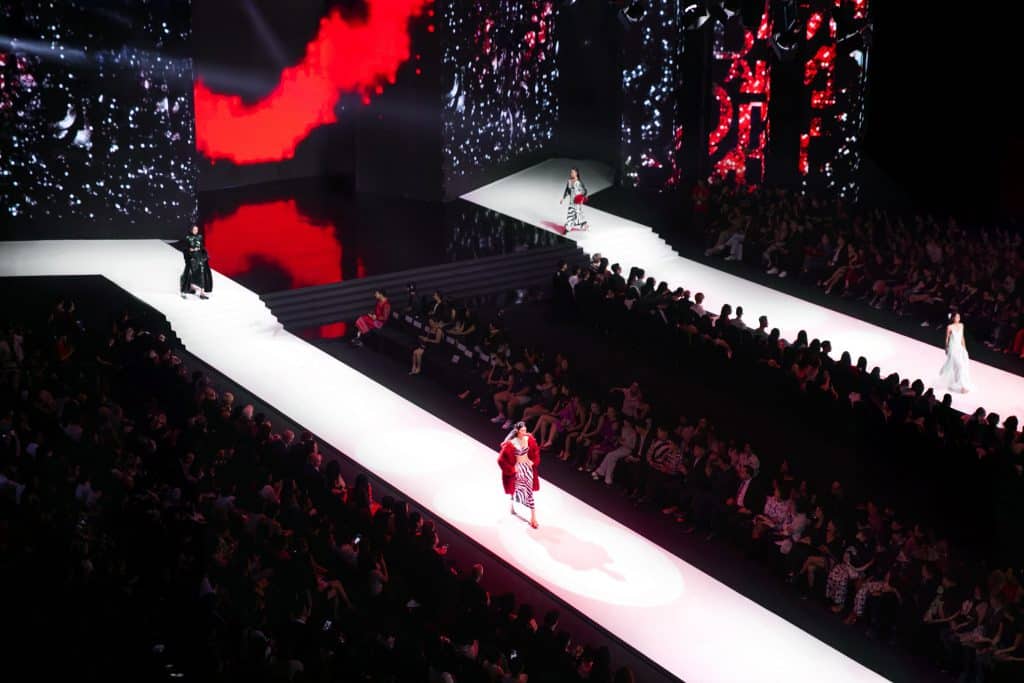 Người mẫu trình diễn trên sàn catwalk trong show diễn thời trang với ánh sáng rực rỡ
