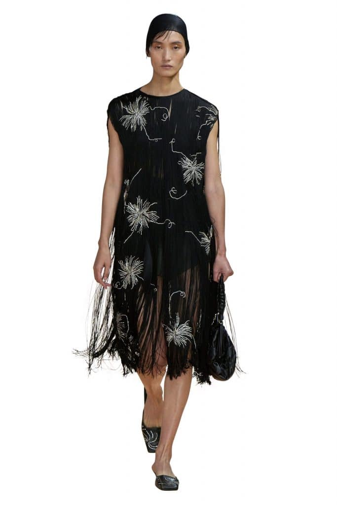 Người mẫu trình diễn váy đen họa tiết hoa trắng và tua rua thời trang Prada