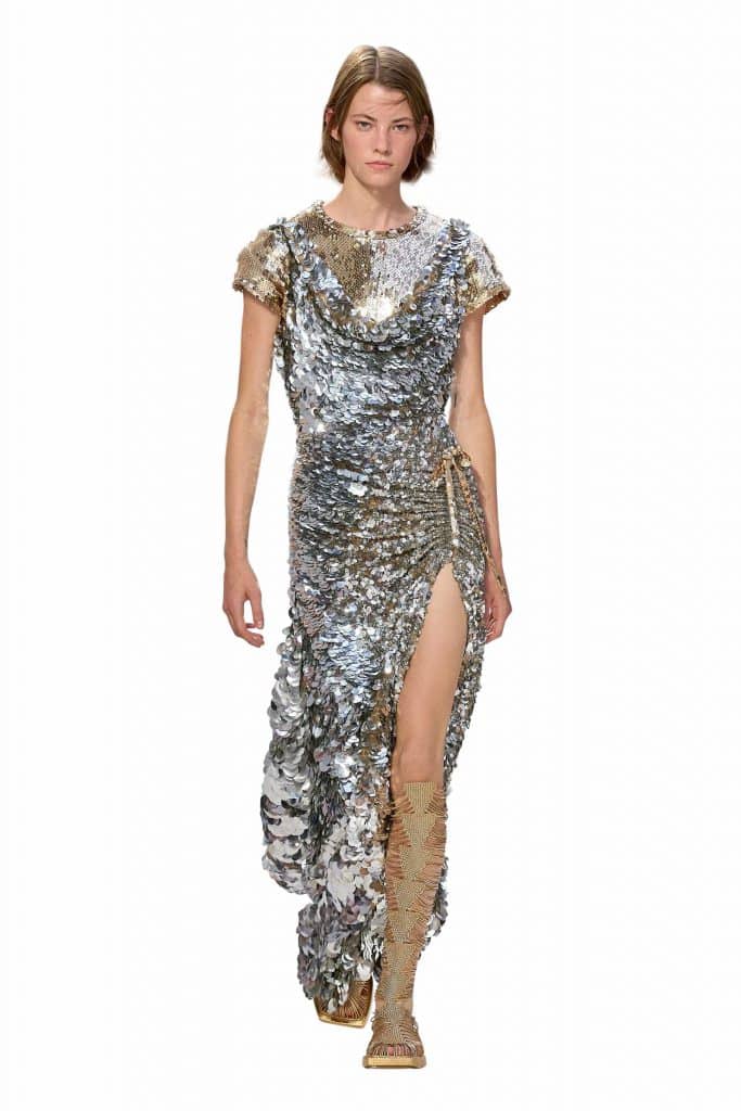 Người mẫu trình diễn váy dạ hội lấp lánh đính sequin và đôi ủng cao cổ