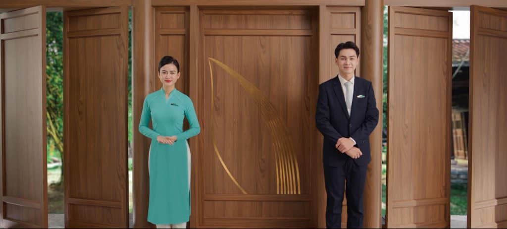 Tiếp viên hàng không nam nữ đứng trước cửa gỗ chạm khắc hình chim bay