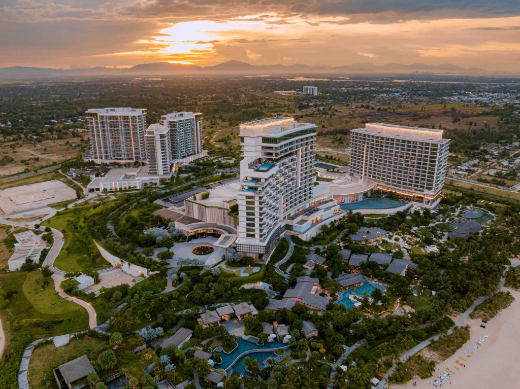 Aerial view of Hoiana Resort with pools villas and surrounding landscape at sunset