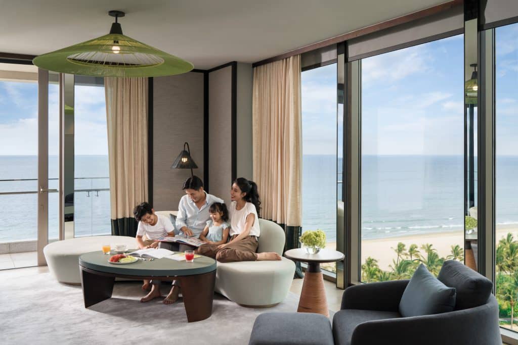 A family relaxes together in a luxurious hotel room overlooking a beautiful beach