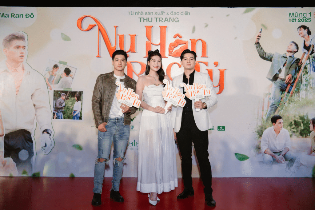 Ba diễn viên chính phim "Nụ Hôn Bạc Tỷ" tạo dáng trên thảm đỏ trước backdrop phim