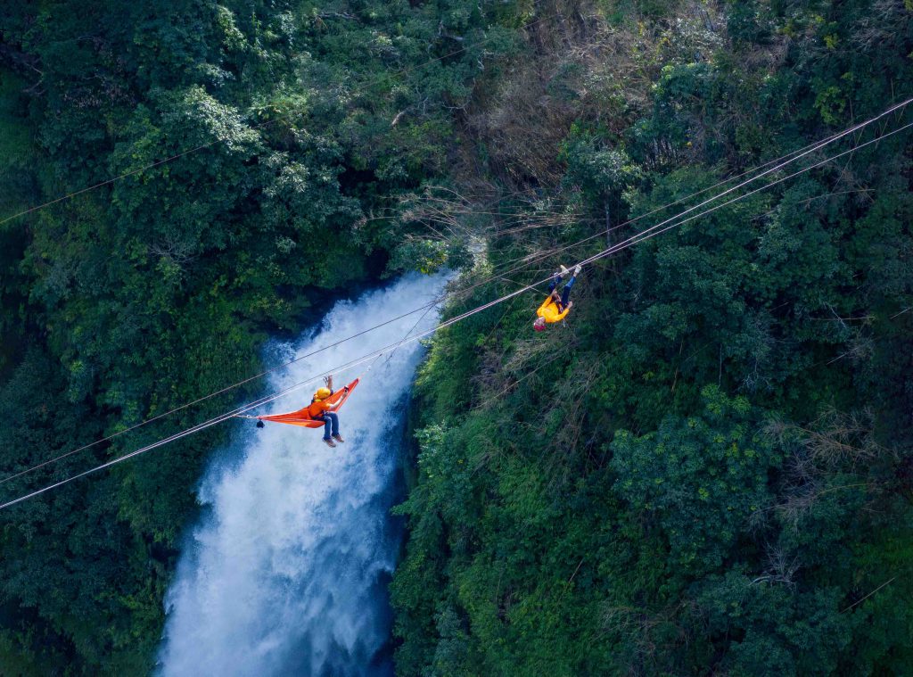 Hai người chơi zipline trên khung cảnh thác Tad Fane hùng vĩ giữa rừng xanh