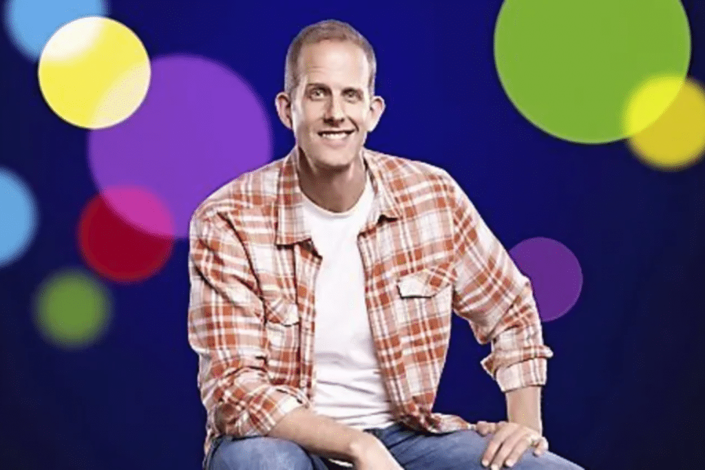 Người đàn ông mặc áo sơ mi ca rô ngồi trước nền các vòng tròn màu sắc