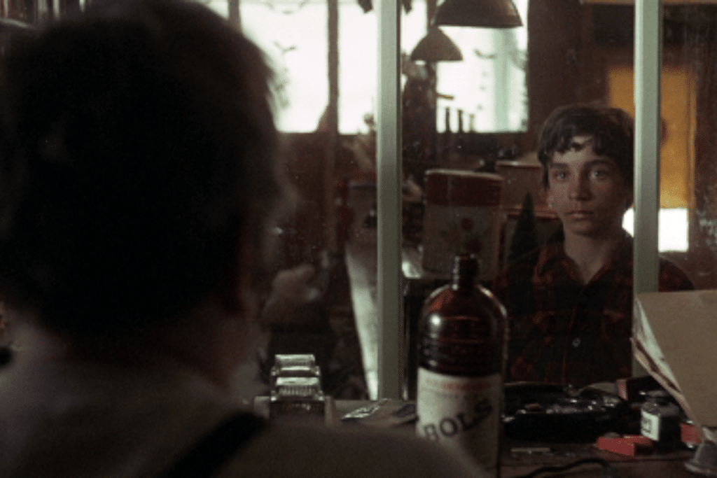 Chàng trai trẻ nhìn vào gương trong một quán bar tối tăm