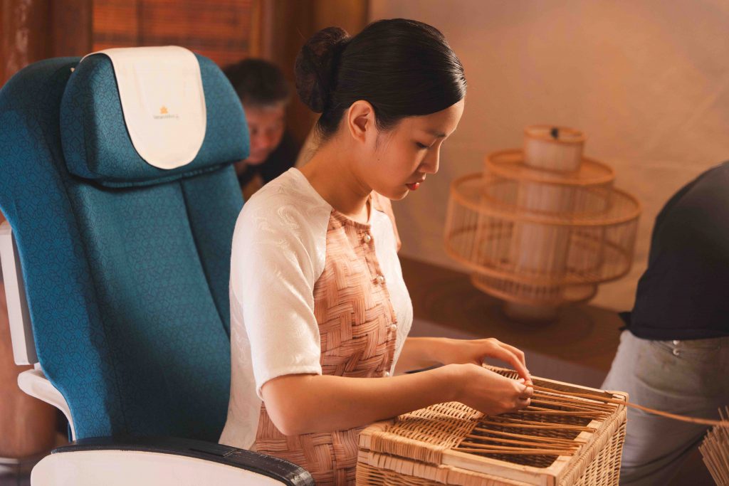 Cô gái đang tỉ mỉ đan mây tre trong không gian ấm cúng mang đậm nét truyền thống