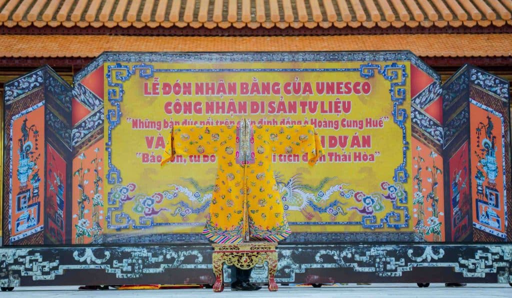 A colorful banner hangs between ornate red pillars in a palace courtyard