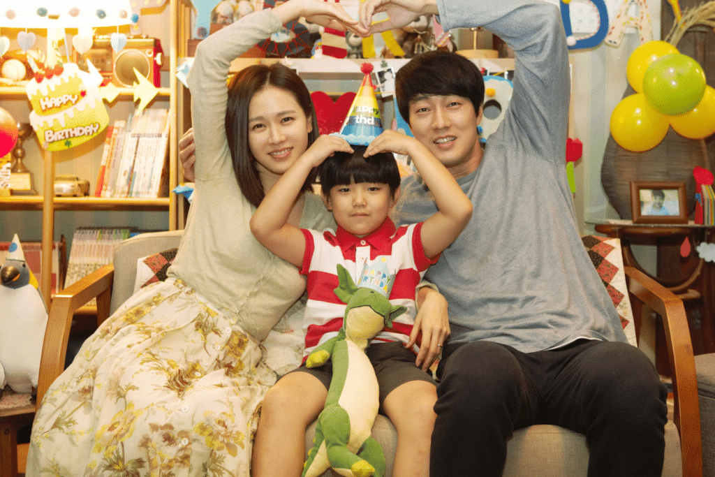 Gia đình trẻ hạnh phúc cùng bé trai tạo dáng trái tim trong buổi sinh nhật