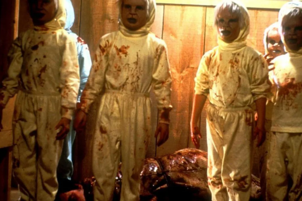 Bốn đứa trẻ mặc đồ bảo hộ trắng dính máu đứng trước một vật thể lớn tối màu