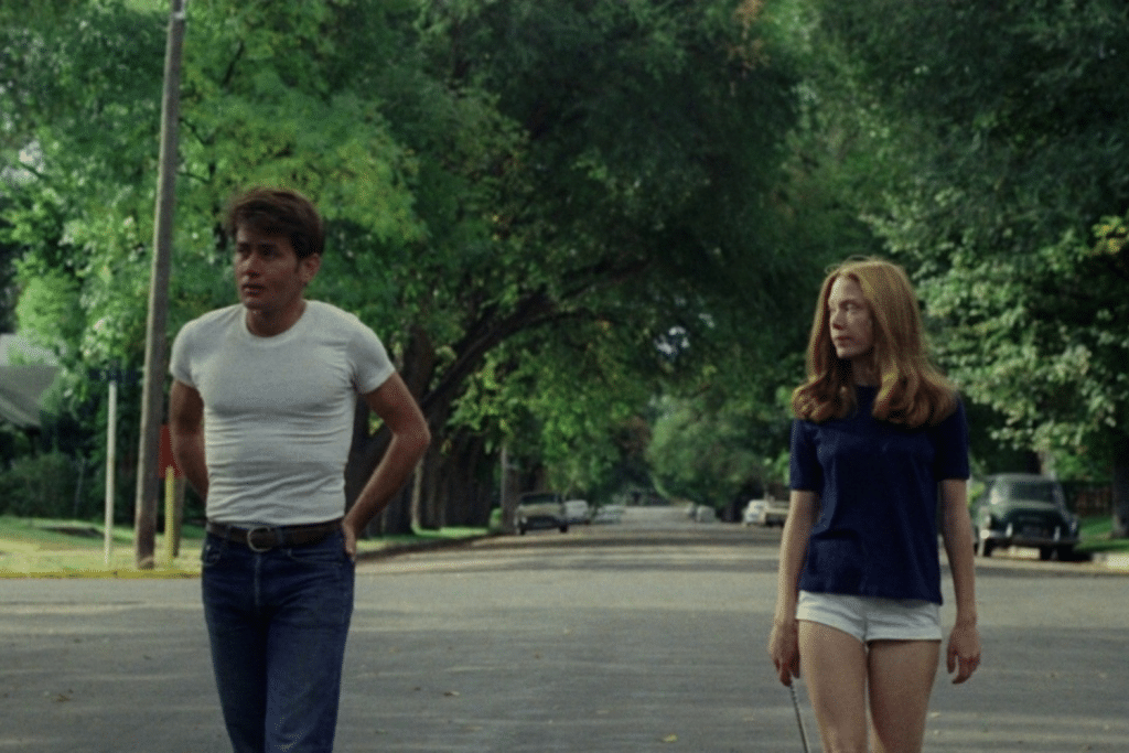 Một cặp đôi trẻ đi trên con đường rợp bóng cây xanh mát trong khu dân cư