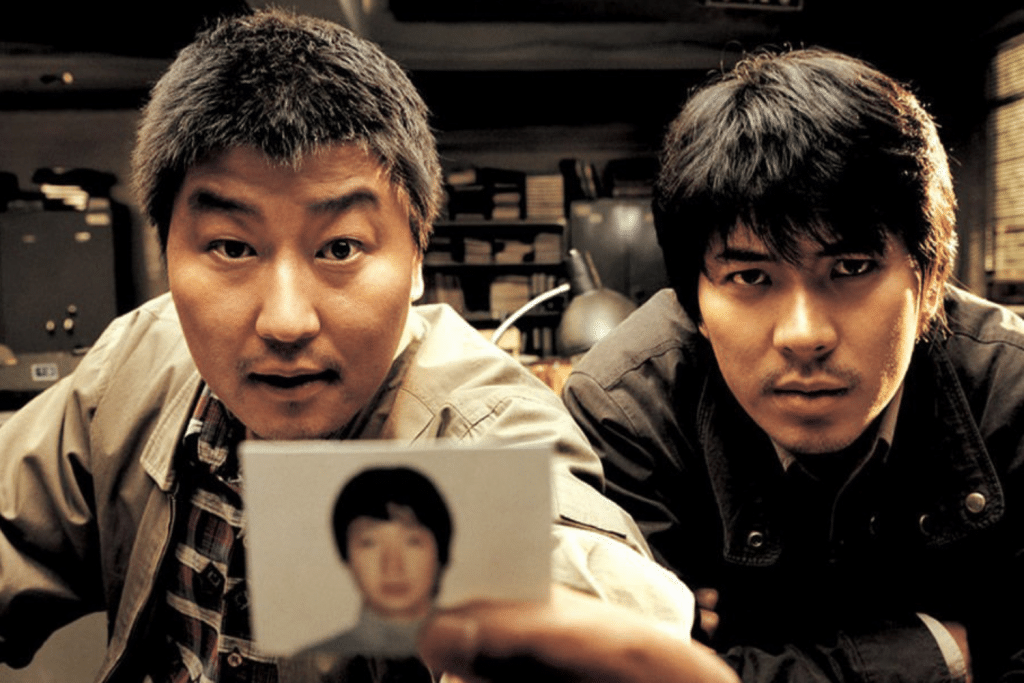 Hai người đàn ông nhìn vào bức ảnh của một người khác với biểu cảm nghiêm túc