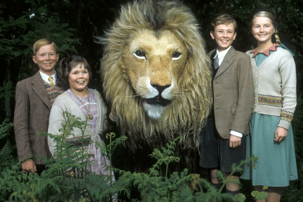 Bốn trẻ em đứng cạnh một con sư tử lớn trong khung cảnh rừng cây xanh mát