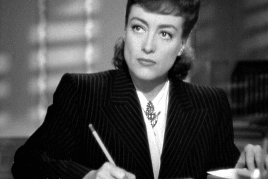 Nữ diễn viên mặc vest và đeo trang sức đang nhìn lên với vẻ suy tư