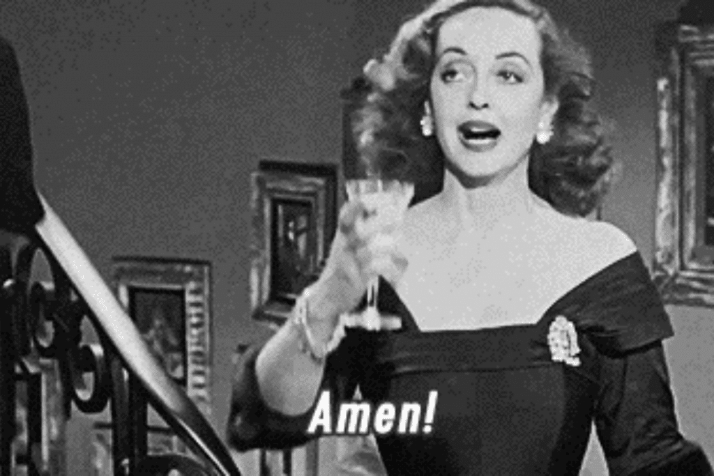 Một phụ nữ trong phim cổ điển giơ ly rượu với vẻ mặt ngạc nhiên và hào hứng