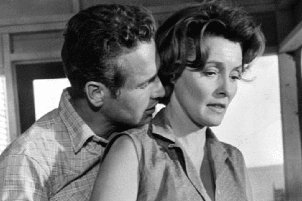 Một người đàn ông thì thầm vào tai người phụ nữ đang buồn bã trong khung cảnh đen trắng