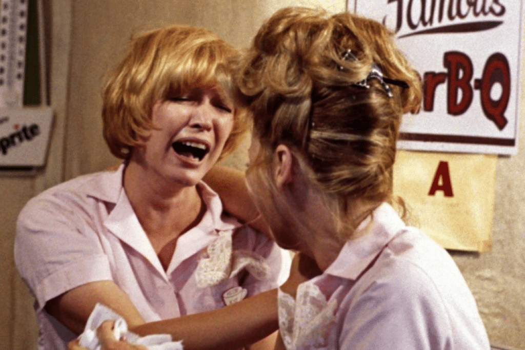 Hai nữ nhân viên nhà hàng cười vui vẻ trong bộ đồng phục màu hồng nhạt