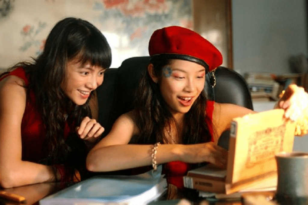 Hai cô gái trẻ vui vẻ cùng xem một cuốn sách nhỏ trên bàn
