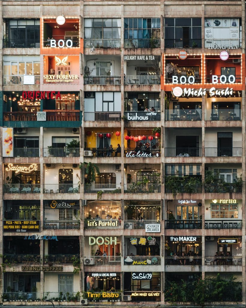 A colorful building facade displays various shop signs and string lights in Vietnam