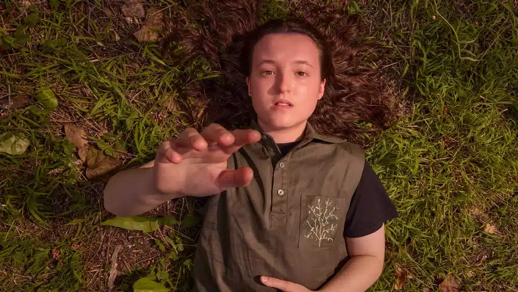 Diễn viên trẻ nằm trên thảm cỏ xanh nhìn thẳng vào ống kính