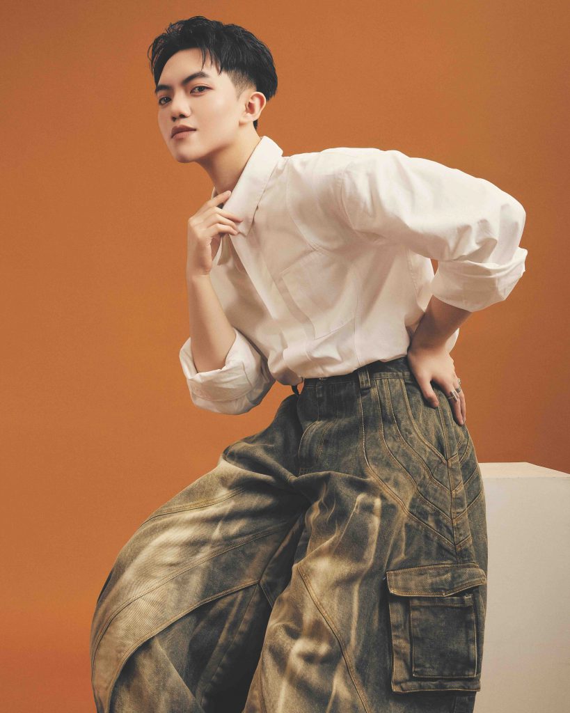 Chàng trai trẻ trung diện áo sơ mi trắng và quần baggy cá tính trên nền cam ấm áp
