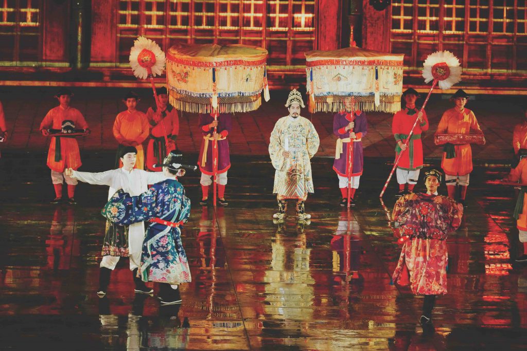 Performers in traditional dress present a cultural show on a wet stage