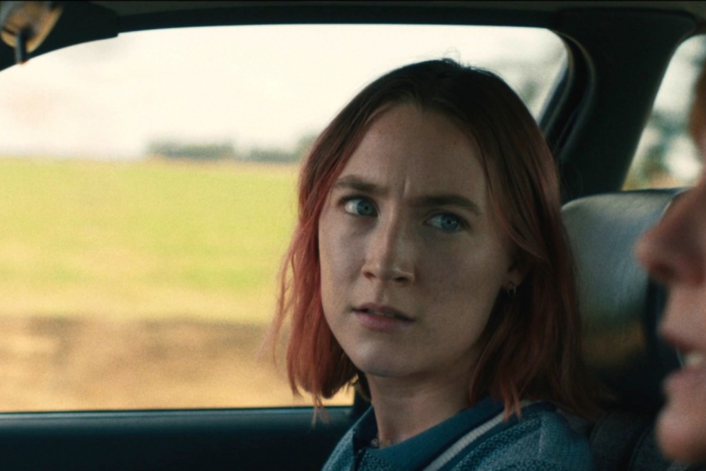 Người phụ nữ tóc đỏ nhìn ra cửa sổ xe với vẻ trầm tư