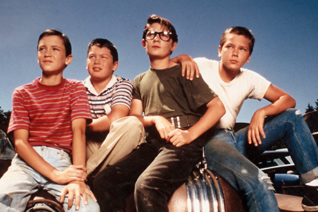 Bốn cậu bé mặc trang phục đời thường tạo dáng trên một chiếc xe hơi cũ