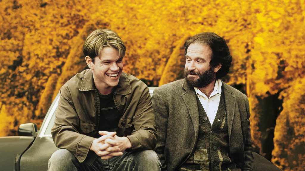 Hai người đàn ông mỉm cười rạng rỡ ngồi cạnh xe tải trên nền lá vàng mùa thu