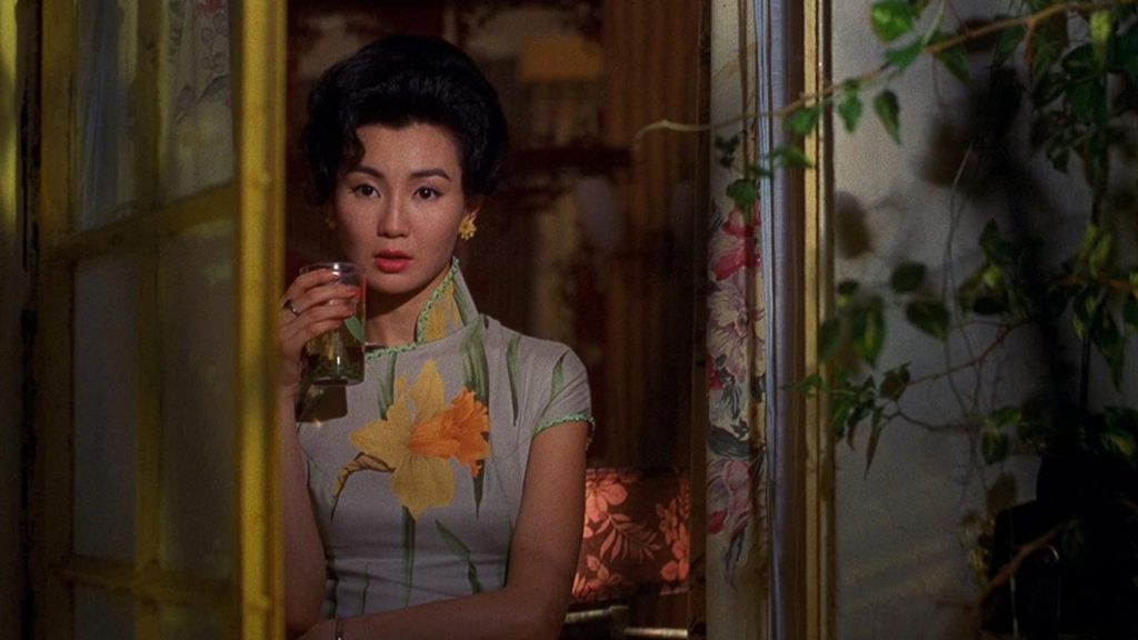 Người phụ nữ mặc áo dài hoa cầm ly nước nhìn sang một bên