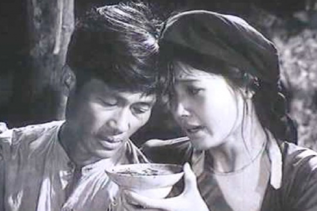 Cảnh phim đen trắng khắc họa đôi nam nữ cùng chia sẻ bát cơm nghèo khó