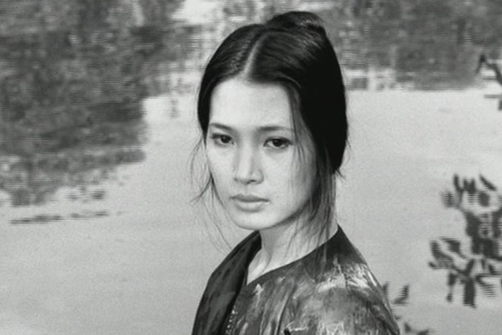 Nữ diễn viên với mái tóc búi cao nhìn thẳng vào ống kính trong một khung cảnh đen trắng