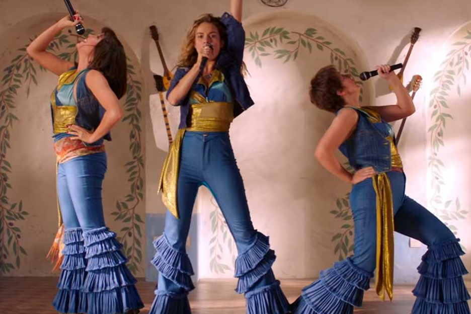 Ba phụ nữ mặc trang phục lấp lánh đang hát vào micro trên sân khấu