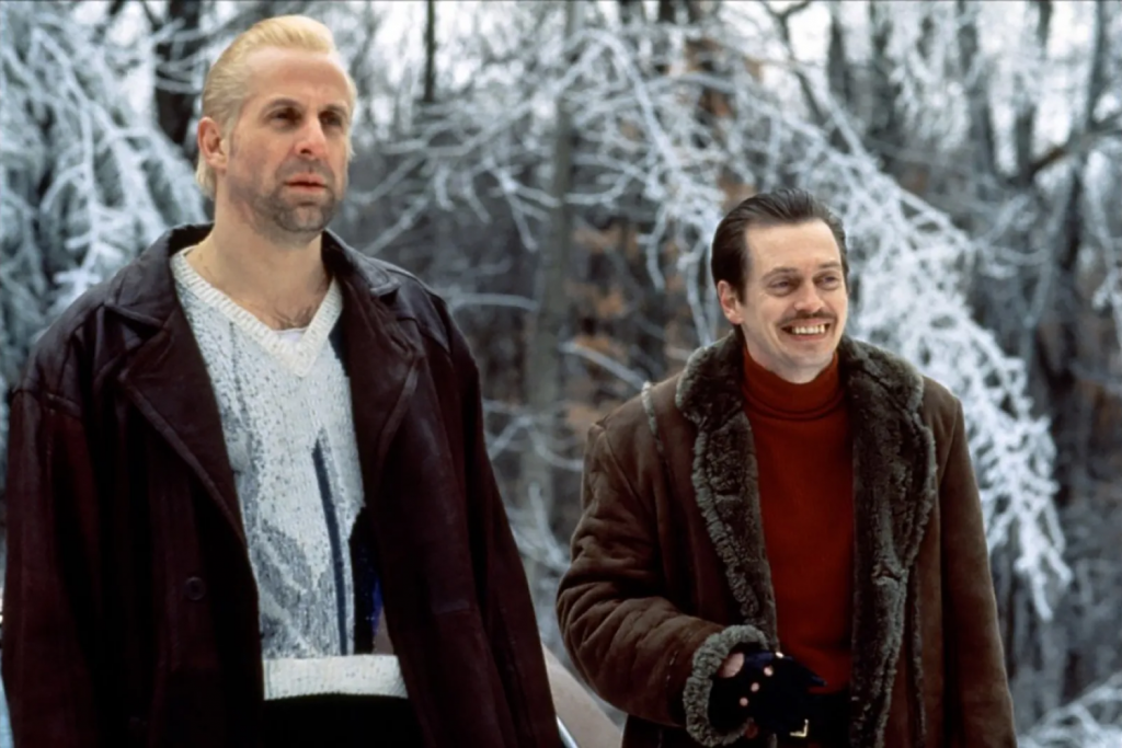 Hai người đàn ông mặc áo khoác da đứng trong khung cảnh rừng cây phủ đầy tuyết